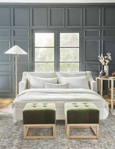 a white couch and ottoman in a room with blue paneling on the wall behind it