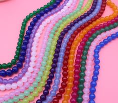 multicolored beads are laid out on a pink surface