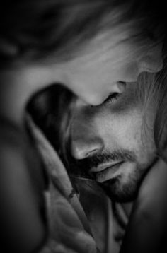 black and white photograph of a man with long hair holding his head to his face