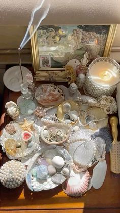 an assortment of seashells and other items on a table with a mirror in the background