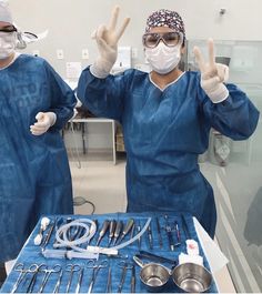 two doctors in scrubs are making the peace sign with their hands and holding utensils