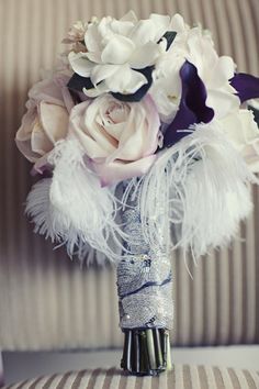 a bridal bouquet with white and purple flowers on a striped couch in the background