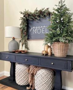 a black console table with christmas decorations on top and a chalkboard sign above it