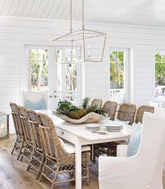 a dining room table with chairs around it and plants on the table in the center