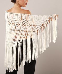 a woman wearing a white crochet shawl with fringes on the sides