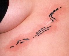 a woman's stomach with an arrow tattoo on her left side ribcage