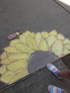 someone is standing on the sidewalk with their feet up in front of a chalk drawing