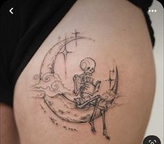 a woman with a skeleton tattoo on her stomach sitting on the moon reading a book