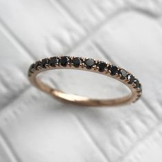 a gold ring with black stones on it sitting on top of a white clothed surface