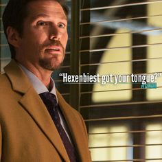 a man in a suit and tie standing next to blinds with a quote on it