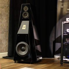 a pair of speakers sitting on top of a wooden floor next to a black curtain