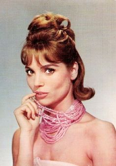 a woman in a pink dress with her hand under her chin