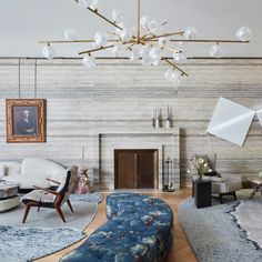 a living room filled with furniture and a fire place under a chandelier hanging from the ceiling