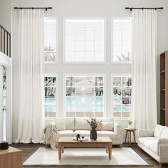 a living room filled with furniture and large windows next to a pool in the background