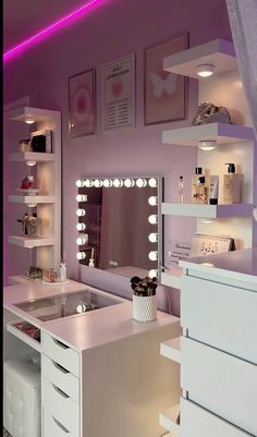 a white vanity with lots of drawers and lights on the wall in a pink room