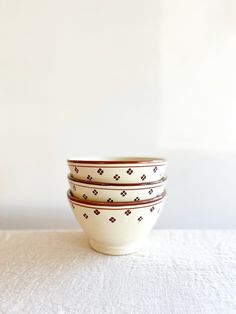 three bowls sitting on top of a white tablecloth covered table next to a wall