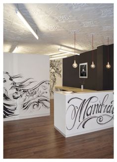 the front desk of an office with decorative murals on the wall and wood flooring