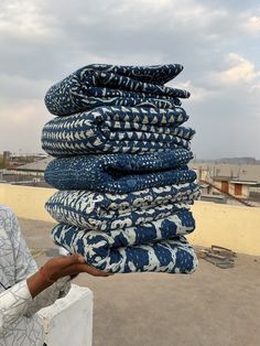 a man holding a stack of blue and white cloths on top of a roof