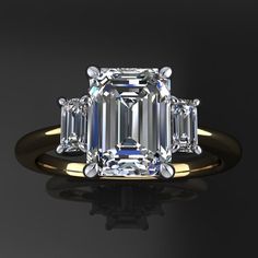 an emerald cut diamond ring on a black surface