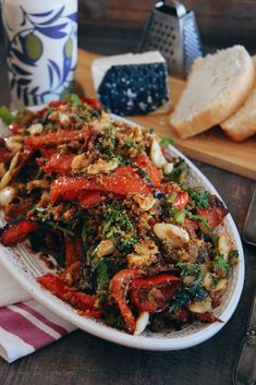 a white plate topped with lots of veggies next to slices of bread on top of a wooden table