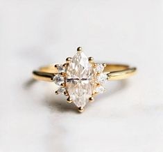 a yellow gold engagement ring with an oval cut diamond surrounded by smaller round brilliant diamonds