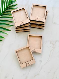 four wooden coasters sitting on top of a white marble table next to a green plant