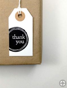 a thank you tag attached to a brown package with white string and black circle on it