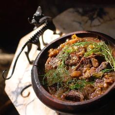 a wooden bowl filled with food on top of a marble counter next to a metal object