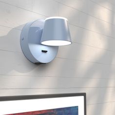 a computer monitor sitting on top of a desk next to a wall mounted light fixture