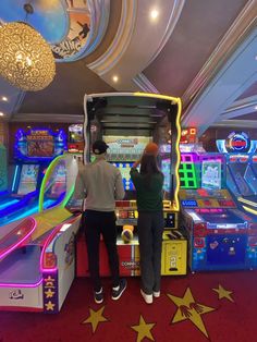 two people standing in front of some pinball machines