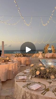 a table set up for an event with lights strung over the tables and in front of the ocean