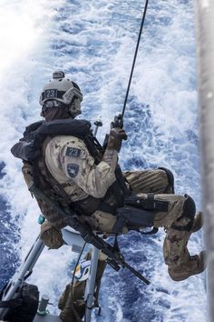 a man sitting on the back of a boat in the ocean while holding onto a fishing pole