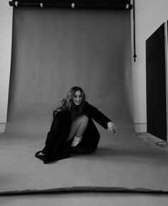 a woman kneeling on the ground in front of a camera