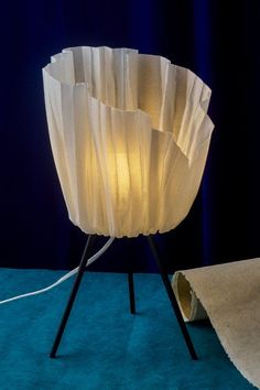 a white lamp sitting on top of a table next to a roll of paper