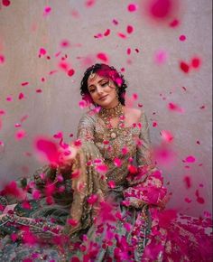 a woman sitting on the ground surrounded by pink confetti and petals in front of her