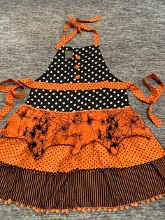 an orange and black dress with polka dots on the bottom is sitting on top of a gray t - shirt