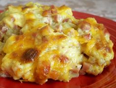 a red plate topped with cheesy hash browns covered in cheese and meats