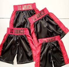 three pairs of black and red boxing shorts with the word dance written on each side