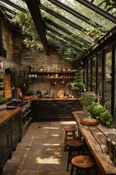 a kitchen filled with lots of green plants and wooden tables under a glass ceilinged area