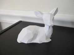 an origami rabbit sitting on top of a black table next to a white wall