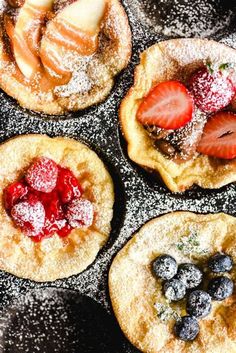 four pancakes covered in powdered sugar and fruit