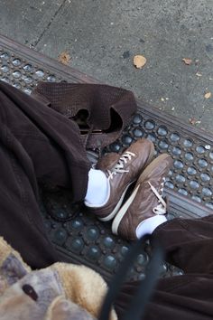 a person's shoes and pants are sitting on the ground next to a metal grate