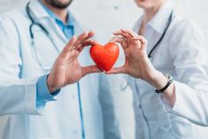 two doctors holding up a red heart in their hands