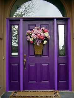 a purple front door with flowers in a basket