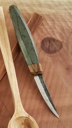 two wooden spoons sitting on top of a cutting board next to a large knife