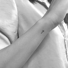 a person with a small cross tattoo on their arm