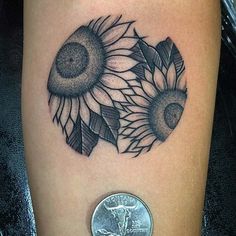 a small sunflower tattoo on the leg with a coin next to it and a penny