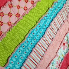 a close up of many different types of quilts on a table top with pink, green and blue fabrics