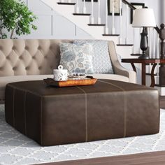 a brown ottoman sitting on top of a wooden floor next to a white stair case