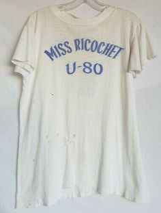 VINTAGE PRODUCTIONS Present 1960's Miss Ricochet U-80 Racing Team T-shirt. Short sleeve, thin cotton body. White body with blue printed designs n the front and back. Has some staining and two holes in the lower front that look like they had been hand repaired before. No tags. Has been well worn and used. Shoulder to shoulder: 17 1/2 inches armpit to armpit: 18inches sleeve length: 5 inches Bottom of collar to hem: 26 inches We only ship via Priority mail in in the US and out side the US it is do Vintage White T Shirt, Bar Merch, Sonic Youth Shirt, Haircut Shag, Pixie Cut Styles, Vintage Tee Shirts, Wardrobe Pieces, Americana Fashion, Team T Shirts